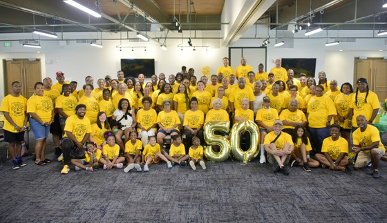 The Bennett family gathered in yellow reunion t-shirts around gold balloons reading 50